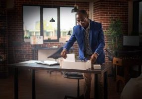 Person getting fired and gathering belongings in box to leave business job. Disappointed man being discharged from work and packing up office things. Frustrated adult being dismissed