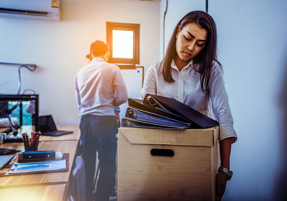 Sad fired businesswoman holding box with her stuff after being dismissed