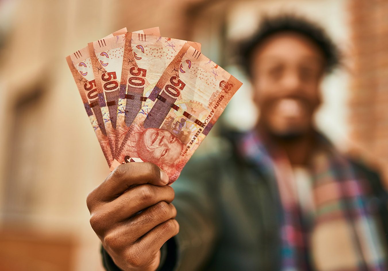Young african american man smiling happy  holding south africa rands banknotes at the city